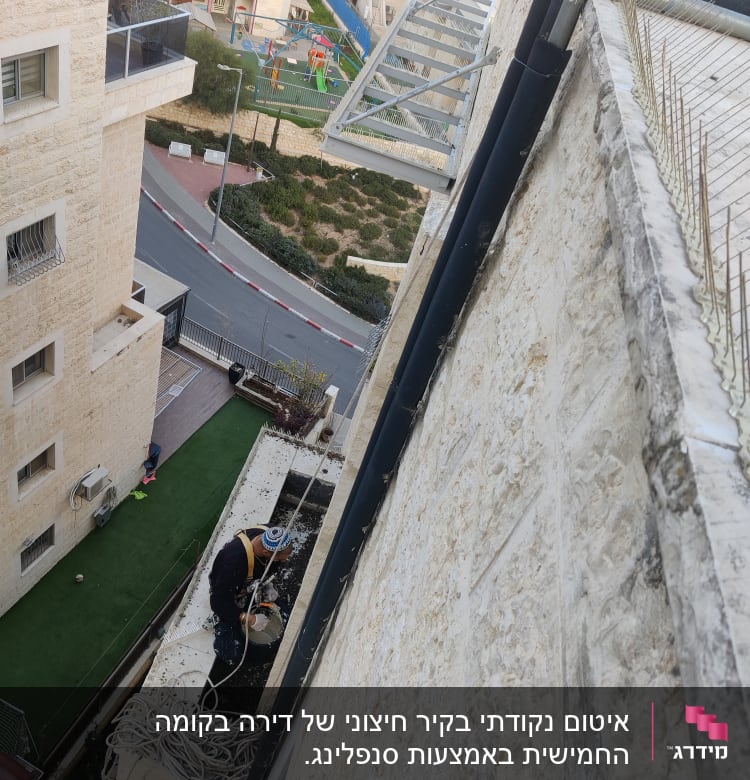 אדם עובד על איטום קיר חיצוני עם דלי וחומרים